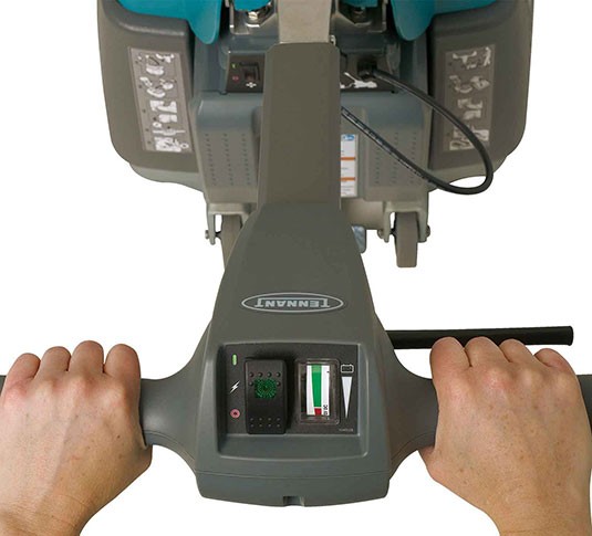 A Tennant T1B Battery Walk-Behind Scrubber cleaning a convenience store.